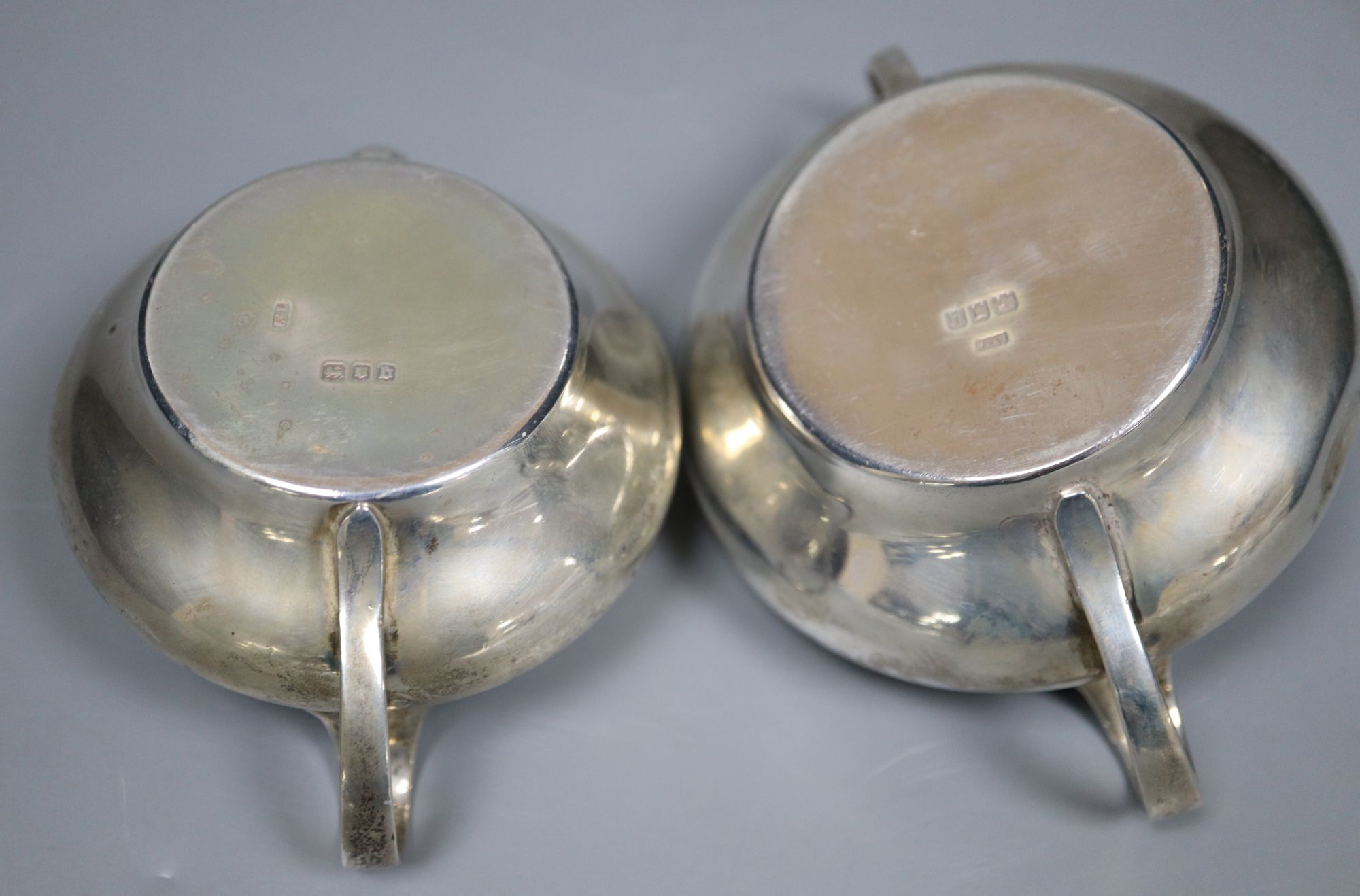 A George V silver sugar bowl and cream jug, London 1935 and a pair of Edwardian silver salt and pepper pots, London 1905,